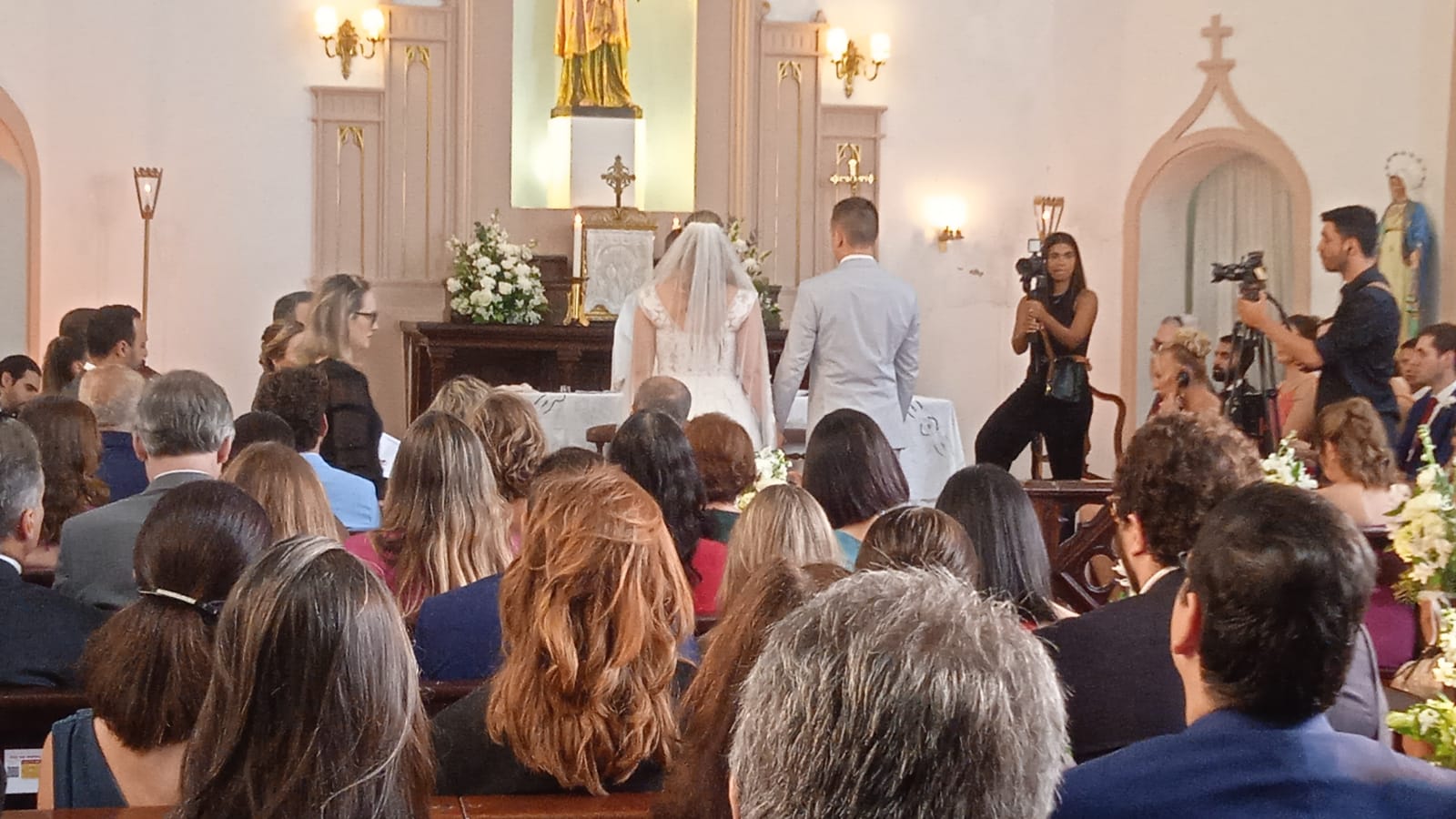casal se casando e vários convidados assistindo à cerimônia