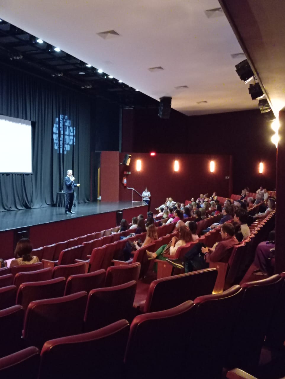 pessoa sobre o palco dando uma palestra no Centro Educacional Leonardo da Vinci
