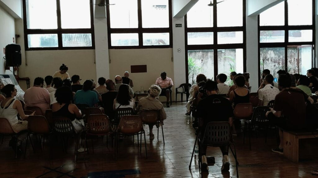 pessoas em uma sala acompanhando a conversa do Fred Moten e Stefano Harney
