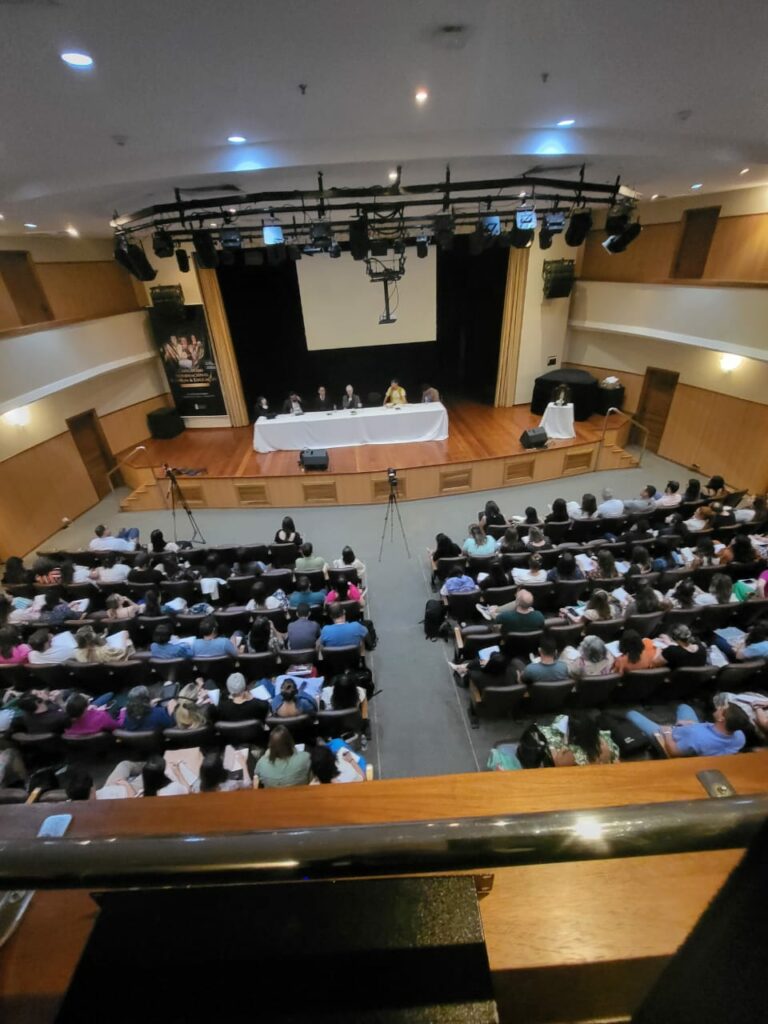 grupo de pessoas acompanhando a palestra no auditório do Colégio Maria Imaculada