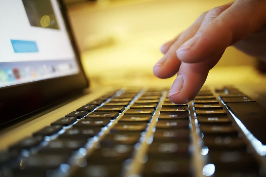 Dedo quase tocando uma tecla de um notebook, representando o uso da editoração eletrônica no processo de tradução de documentos.
