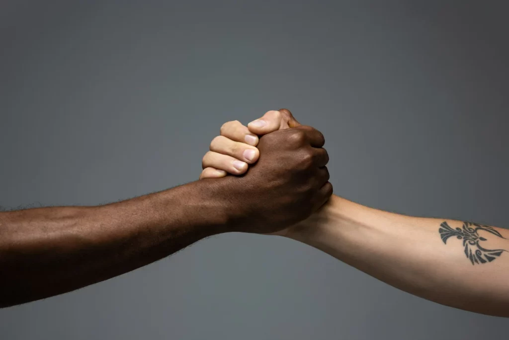 aperto de mão entre uma pessoa negra e pessoa branca