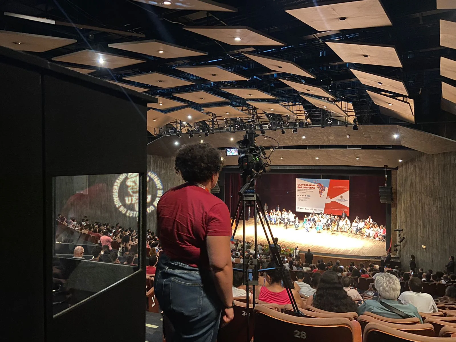 pessoa no teatro gravando a apresentação do evento sobre igualdade racial e representatividade