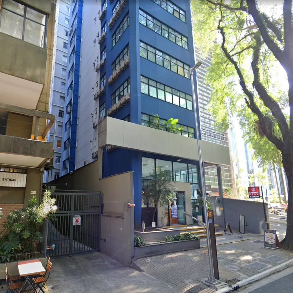 Fachada da unidade da One Translations em São Paulo na Alameda Santos, vista urbana com árvores e edifício comercial azul.